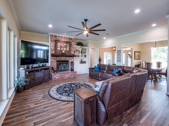 living room with a brick fireplace, ceiling fan, dark hardwood / wood-style floors, and ornamental molding