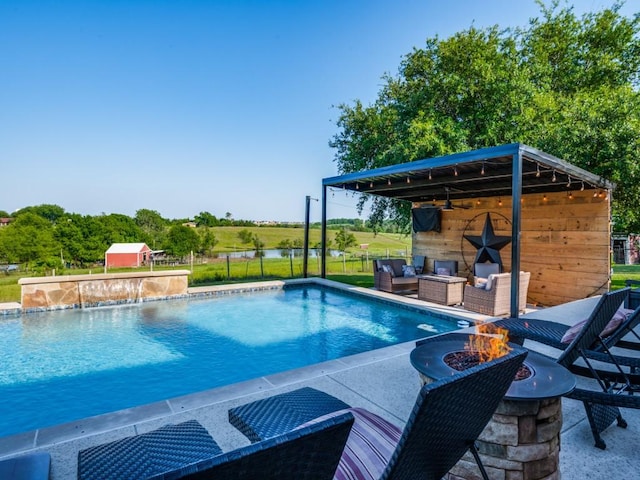 view of pool with pool water feature, an outdoor structure, and an outdoor living space with a fire pit