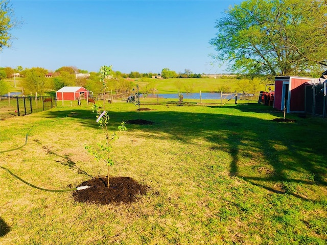 view of yard featuring a rural view, a water view, and an outdoor structure