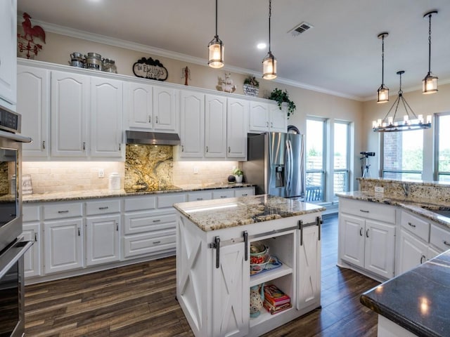 kitchen featuring a center island, stainless steel fridge, white cabinets, hanging light fixtures, and ornamental molding