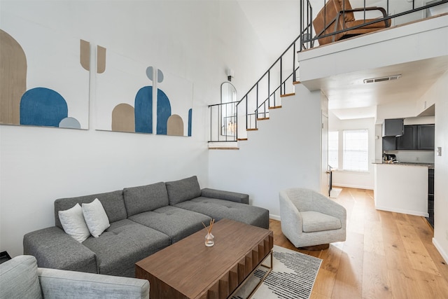 living room with a high ceiling and light hardwood / wood-style floors