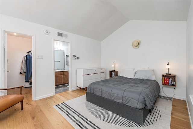 bedroom with vaulted ceiling, ensuite bathroom, a spacious closet, light hardwood / wood-style floors, and a closet