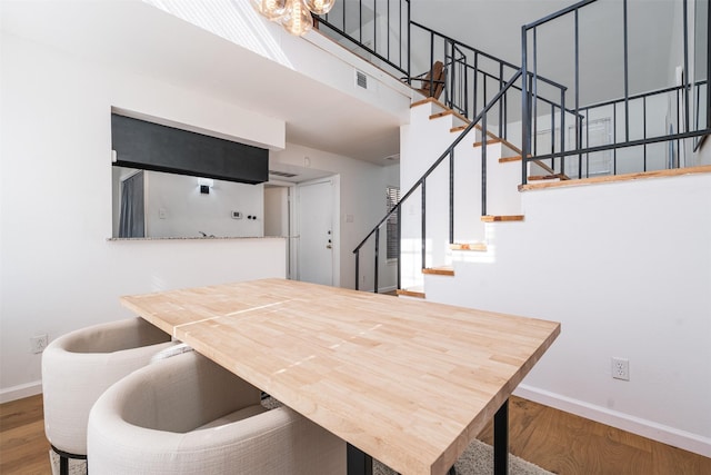 dining room featuring a towering ceiling and wood-type flooring