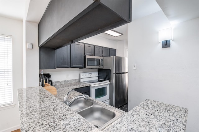 kitchen with stainless steel appliances, light stone countertops, sink, and kitchen peninsula