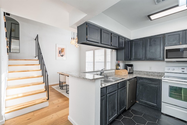 kitchen with appliances with stainless steel finishes, sink, dark hardwood / wood-style flooring, kitchen peninsula, and light stone countertops