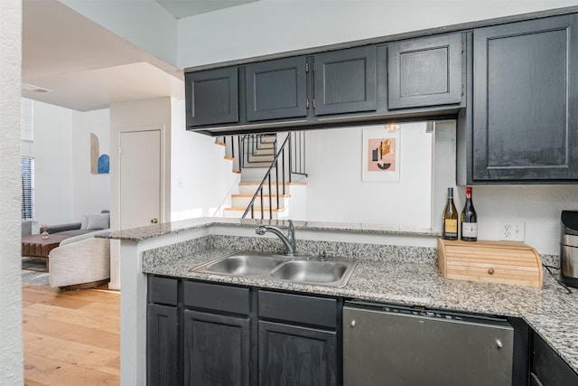 kitchen featuring kitchen peninsula, dishwasher, sink, light stone counters, and light hardwood / wood-style floors