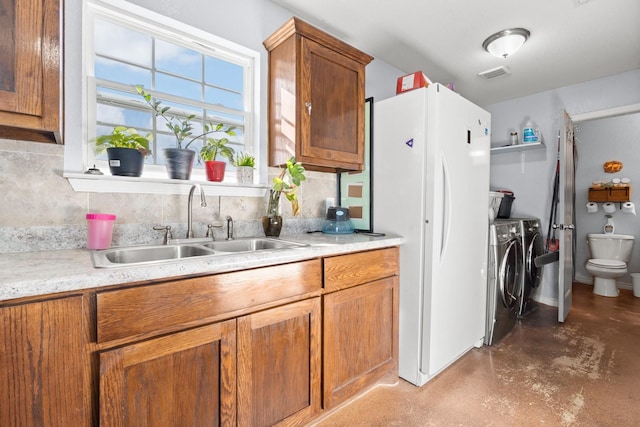 kitchen with sink, decorative backsplash, independent washer and dryer, and white refrigerator