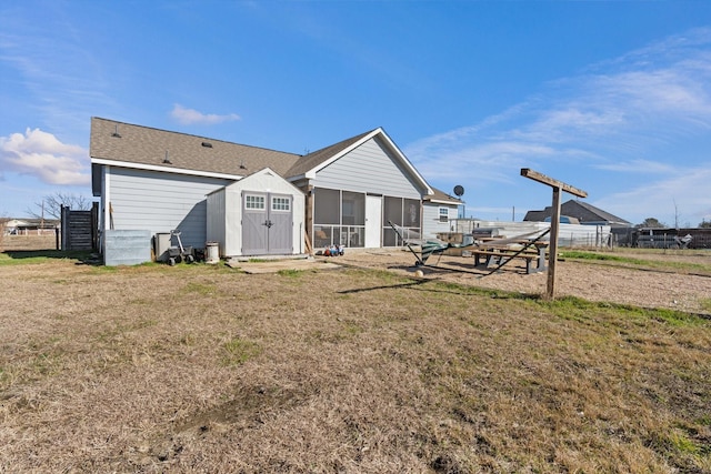 rear view of house with a storage shed, a lawn, and a sunroom