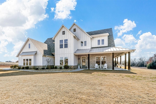 modern farmhouse featuring board and batten siding, a standing seam roof, and brick siding