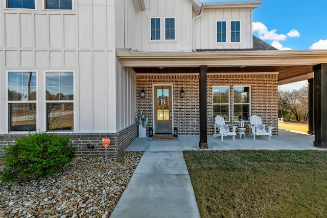 view of exterior entry featuring brick siding, board and batten siding, and a lawn