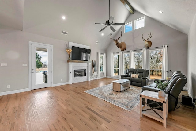 living room with a wealth of natural light, wood finished floors, a glass covered fireplace, and visible vents