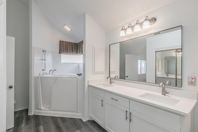 bathroom with vanity, hardwood / wood-style floors, vaulted ceiling, and a bathing tub