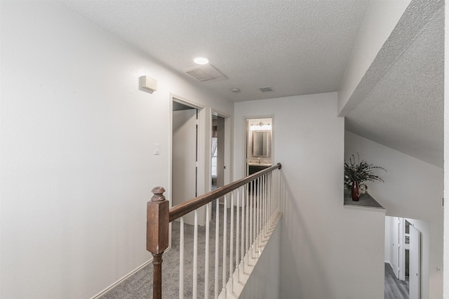 corridor featuring dark colored carpet and a textured ceiling