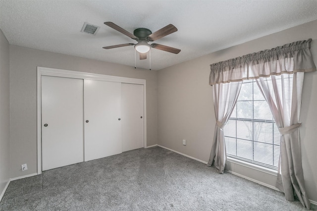 unfurnished bedroom with multiple windows, carpet flooring, a textured ceiling, and a closet