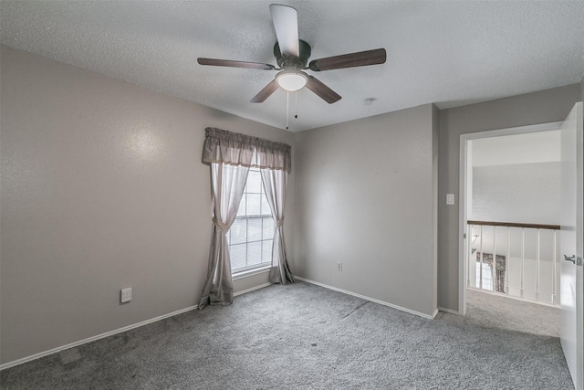 carpeted empty room featuring ceiling fan and a textured ceiling