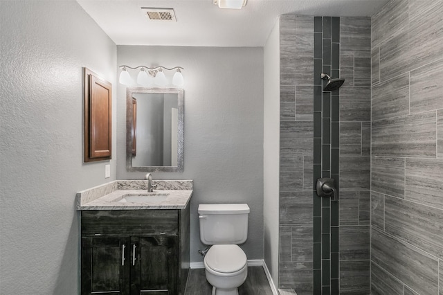 bathroom featuring tiled shower, vanity, and toilet