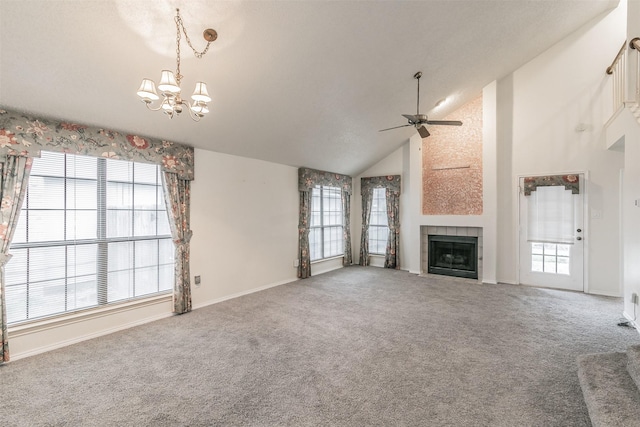 unfurnished living room with a tiled fireplace, ceiling fan with notable chandelier, high vaulted ceiling, and carpet flooring