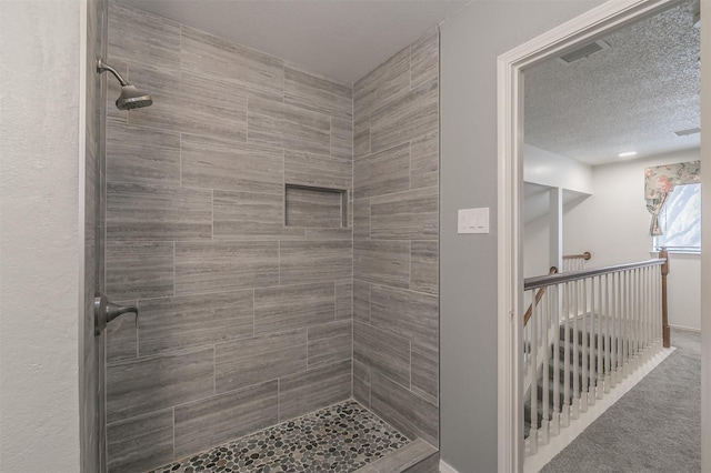 bathroom with tiled shower and a textured ceiling