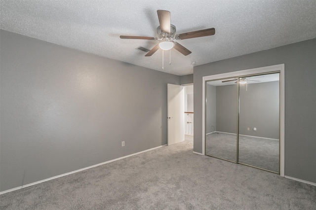 unfurnished bedroom featuring ceiling fan, light colored carpet, a closet, and a textured ceiling