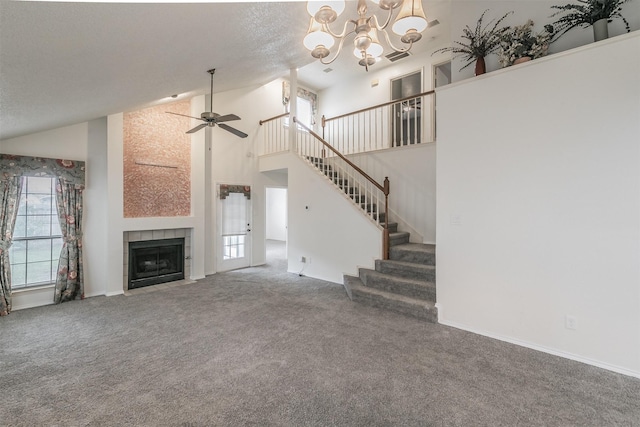 unfurnished living room with high vaulted ceiling, dark colored carpet, a fireplace, a textured ceiling, and ceiling fan with notable chandelier