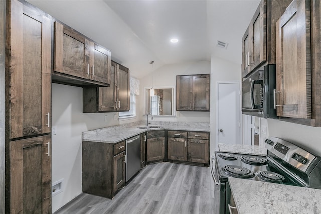 kitchen with appliances with stainless steel finishes, pendant lighting, lofted ceiling, sink, and light hardwood / wood-style flooring