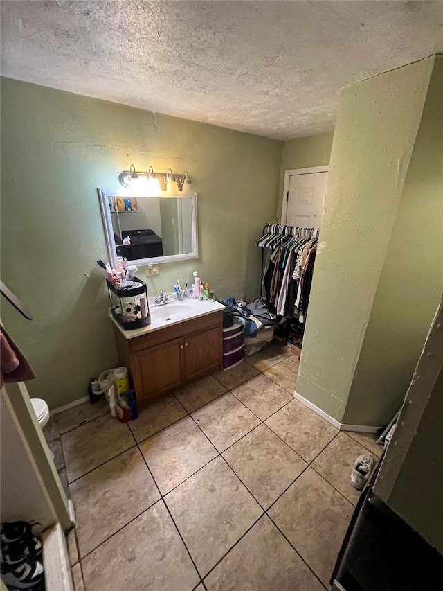 bathroom with tile patterned flooring, vanity, baseboards, and a textured ceiling