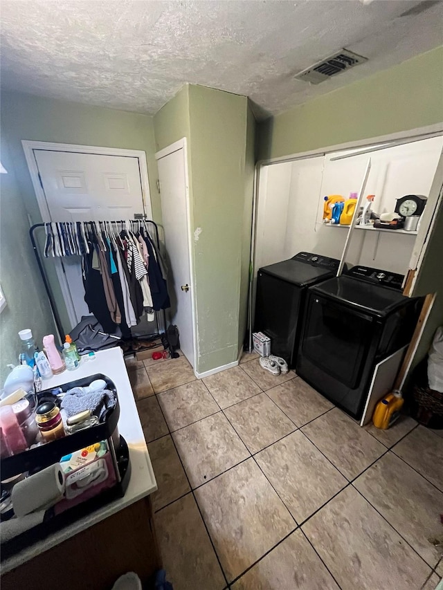 washroom featuring visible vents, light tile patterned floors, laundry area, washer and dryer, and a textured ceiling