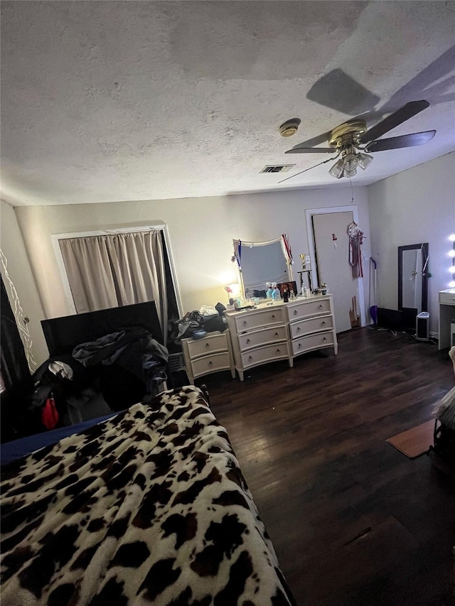 bedroom with ceiling fan, wood finished floors, visible vents, and a textured ceiling