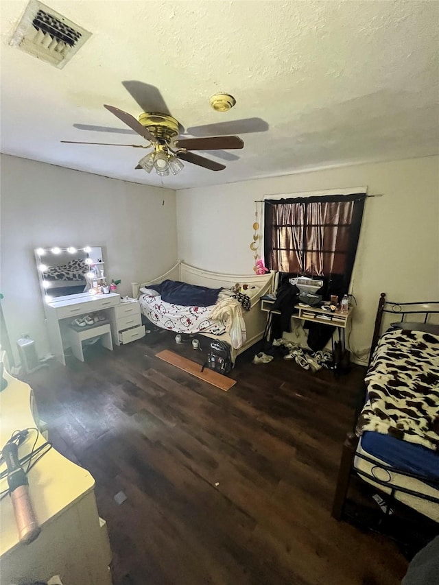 bedroom featuring visible vents, a textured ceiling, ceiling fan, and wood finished floors