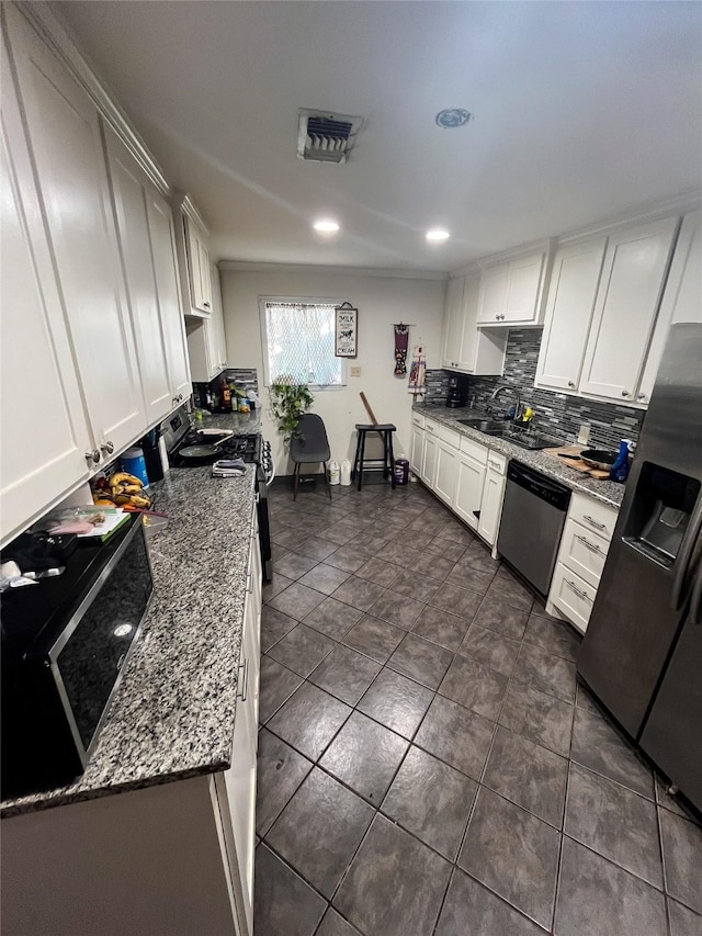 kitchen with tasteful backsplash, visible vents, appliances with stainless steel finishes, white cabinets, and a sink