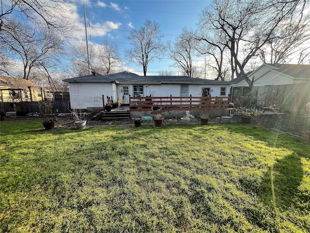 back of property featuring a wooden deck, a lawn, and fence