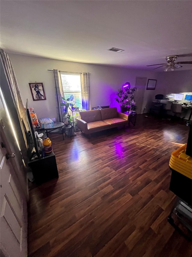 living room with visible vents, wood finished floors, and a ceiling fan