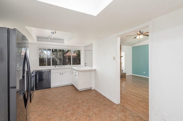 kitchen with black appliances, white cabinetry, sink, light tile patterned floors, and a tray ceiling