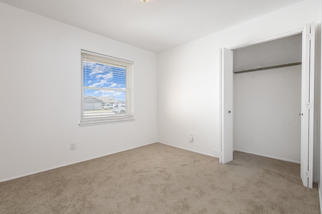 unfurnished bedroom featuring light colored carpet and a closet