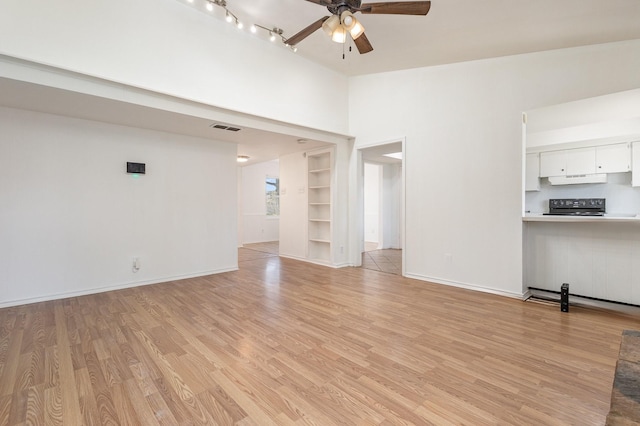 unfurnished living room with lofted ceiling, built in shelves, light hardwood / wood-style floors, and ceiling fan