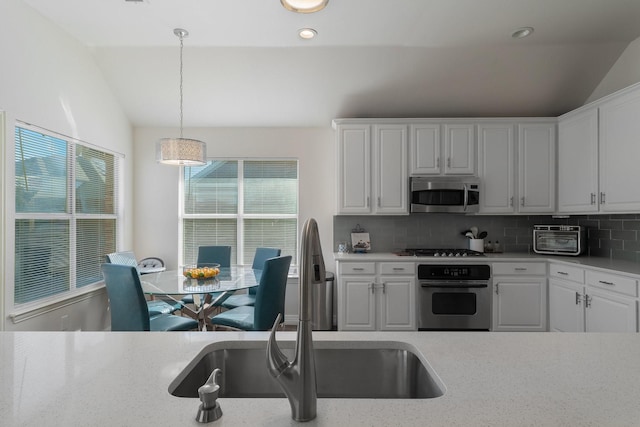 kitchen featuring pendant lighting, lofted ceiling, stainless steel appliances, and white cabinets