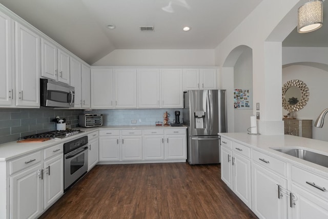 kitchen featuring sink, appliances with stainless steel finishes, white cabinetry, dark hardwood / wood-style floors, and decorative backsplash