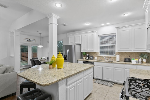 kitchen with pendant lighting, sink, appliances with stainless steel finishes, decorative columns, and white cabinets