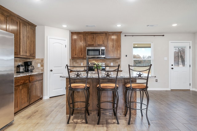 kitchen featuring stainless steel appliances, visible vents, and light stone countertops