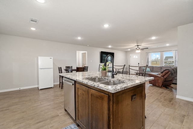 kitchen with sink, white refrigerator, a kitchen island with sink, dishwasher, and light hardwood / wood-style floors