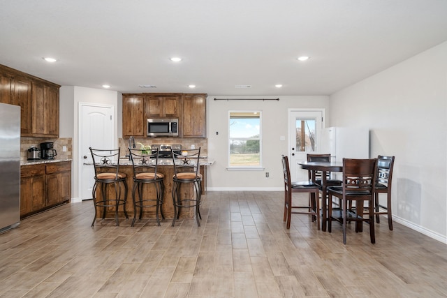 kitchen with backsplash, a kitchen island, a breakfast bar, and appliances with stainless steel finishes