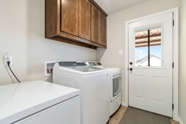 laundry area with washing machine and dryer, cabinet space, and light wood-style flooring