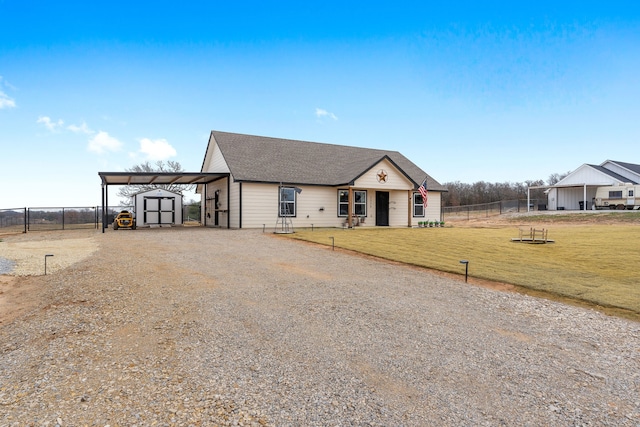 view of front of house with fence, a shed, a carport, driveway, and a front lawn