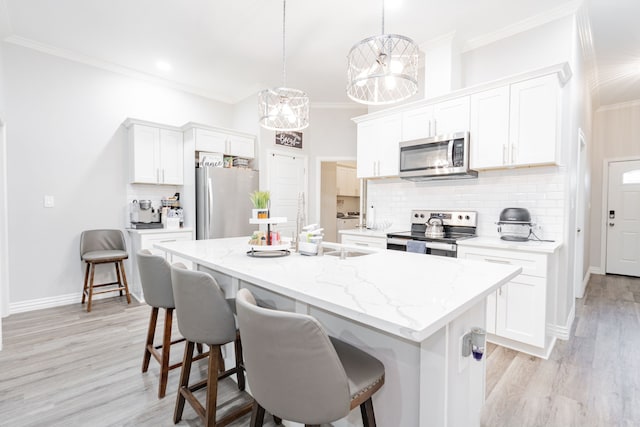 kitchen featuring white cabinetry, appliances with stainless steel finishes, a kitchen island with sink, and hanging light fixtures