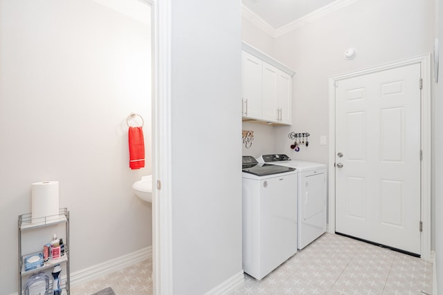 clothes washing area with crown molding, washer and clothes dryer, and cabinets