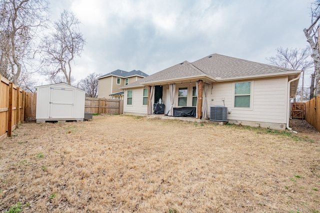 rear view of property featuring central AC unit and a storage shed