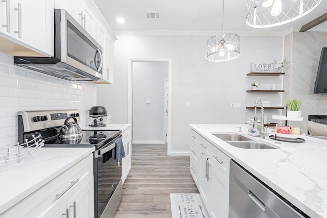 kitchen featuring appliances with stainless steel finishes, sink, pendant lighting, and white cabinets