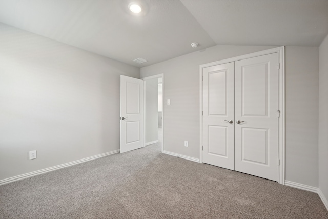 unfurnished bedroom with a closet, vaulted ceiling, and carpet