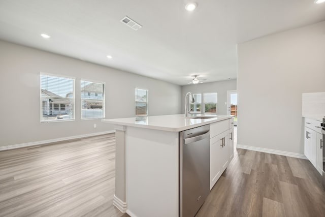 kitchen with sink, white cabinetry, light wood-type flooring, dishwasher, and a kitchen island with sink