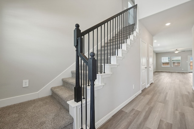 stairs featuring wood-type flooring and ceiling fan